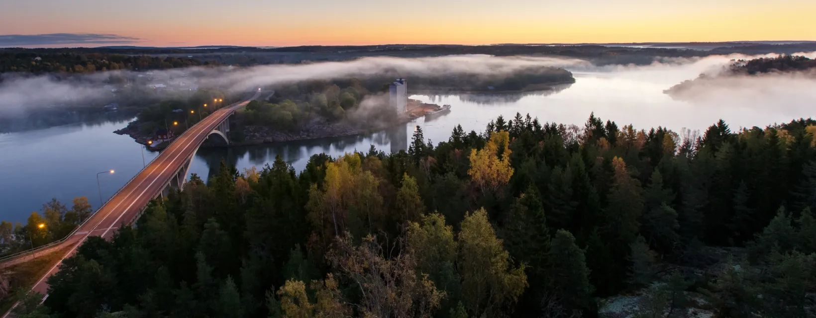 Flygvy över Färjsundsbron en vacker höstmorgon med dimma.