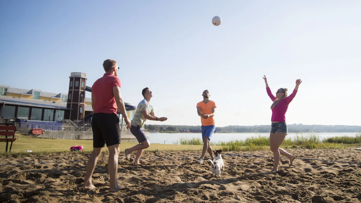 Unga vuxna spelar beachvolleyboll på stranden.