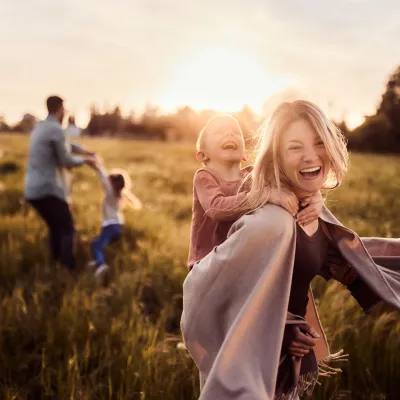 Familj med två barn på en sommaräng i kvällssolen.