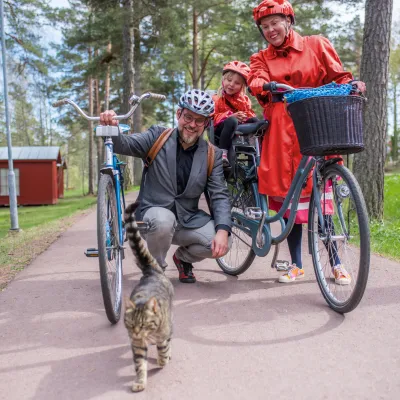 Familj med cykel stannar och hälsar på katt vid Gröna Udden på Åland.