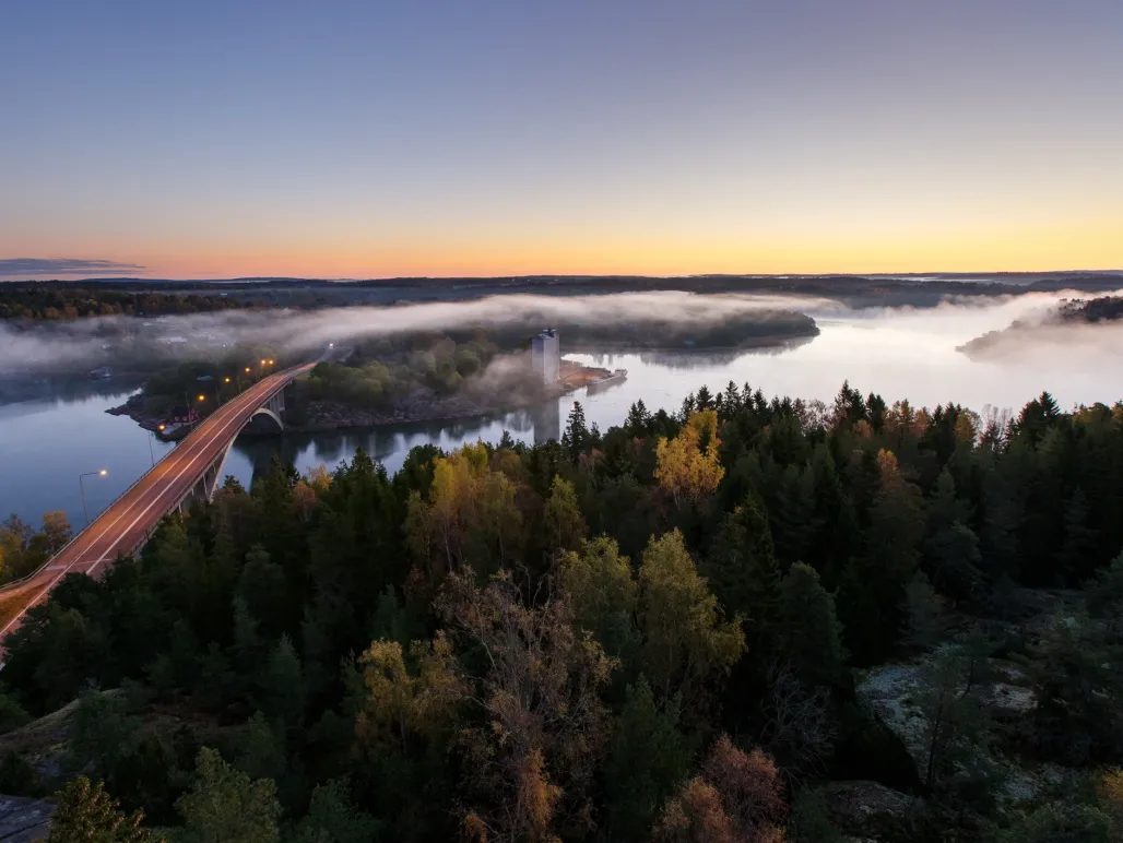 Flygvy över Färjsundsbron en vacker höstmorgon med dimma.